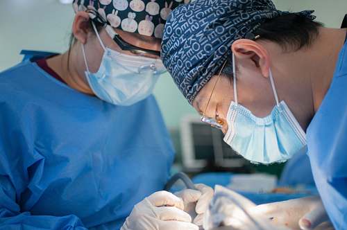 surgeon person in blue scrub suit wearing white and black hat clinic