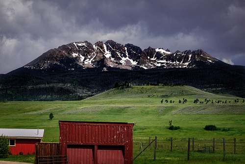 barn landscape photo of green grass field and mountain field