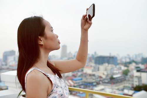 person close-up photography of woman taking photo using smartphone face