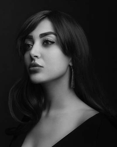person grayscale photo of woman wearing black top in black background black-and-white