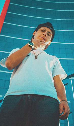 person low angle photo of man wearing white shirt and black cap apparel