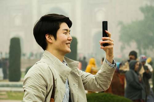person man holding smartphone during daytime face