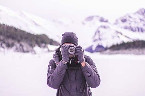 person man in black coat holding DSLR camera photo