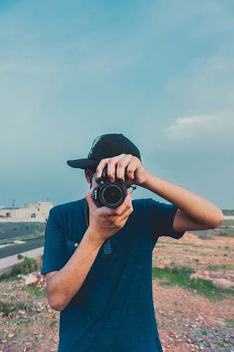 person man in blue Henley shirt holds camera camera