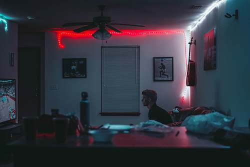 man man sitting inside room near window blinds with lights turned on room