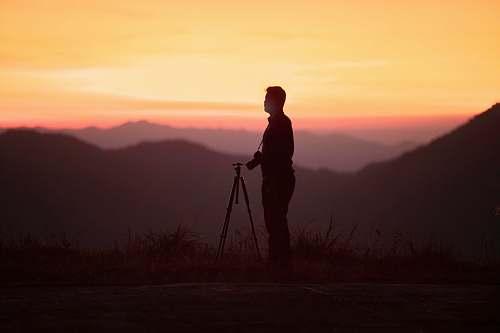 person man standing beside camera tripod tripod