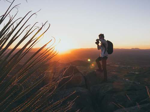 person man standing on cliff during golden hour photographer