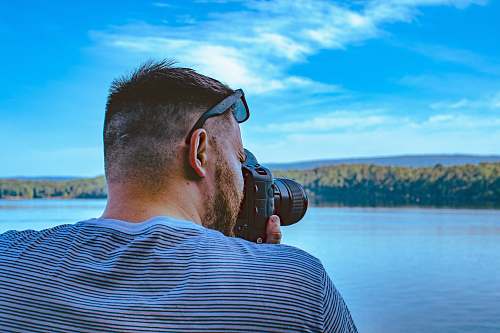 person man taking photo of calm sea under blue and white skies arkansas