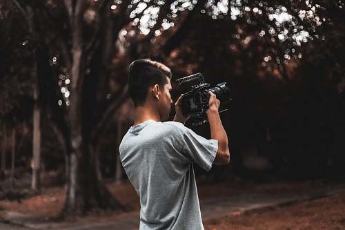person man wearing grey t-shirt holding black camera camera