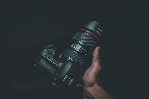 photography person holding black Canon DSLR camera grey