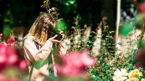 person selective focus photography of woman holding black DSLR camera during daytime photo