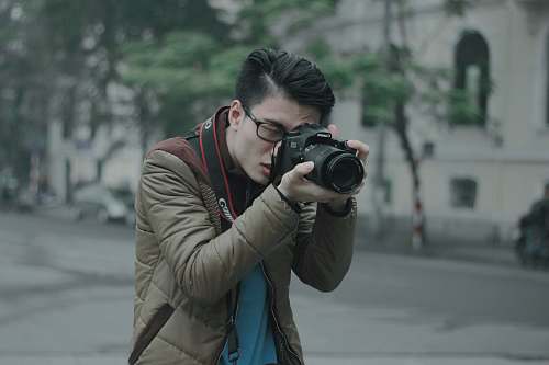person shallow focus photography of man taking photograph holding his camera photographer