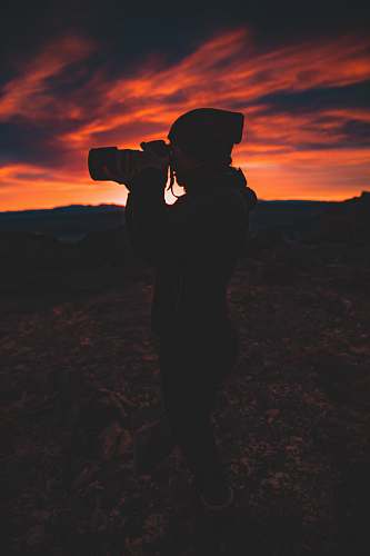 person silhouette of person holding camera during golden hour photo