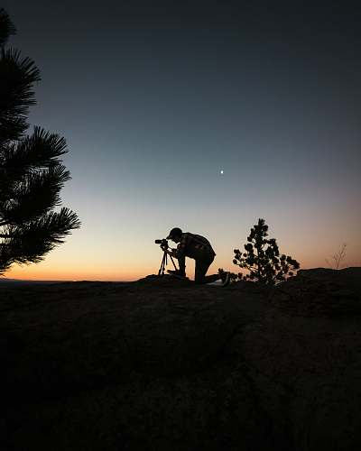 person silhouette photography of man capturing photo during night time photographer