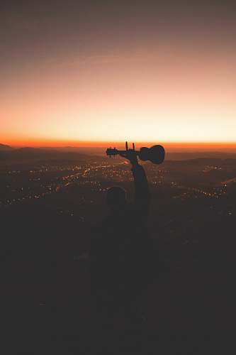 person silhouette photography of person holding guitar photo
