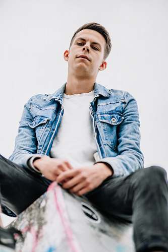 person sitting man wearing white crew-neck shirt looking down during daytime apparel