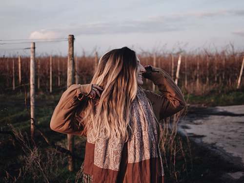 person smiling woman in brown jacket raising both hands during daytime photo