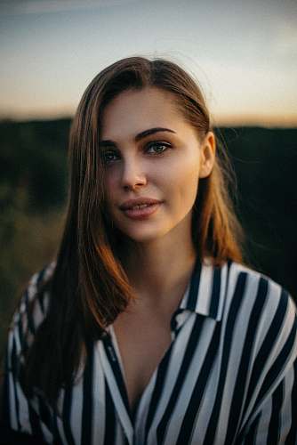 person smiling woman wearing white and black pinstriped collared top face