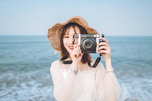 person woman holding camera at the beach electronics