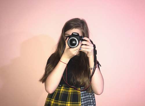 person woman holding camera near pink wall camera
