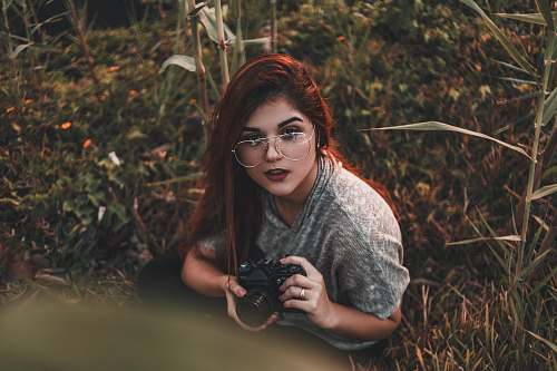 person woman holding camera while sitting on grass camera