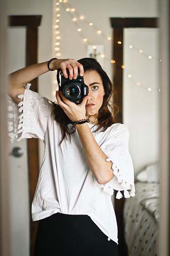 person woman in white top looking through the camera peephole camera
