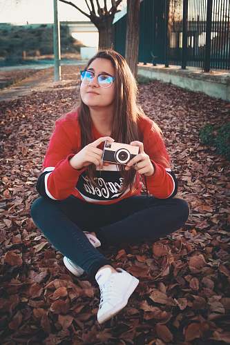 person woman wearing red and black long-sleeved shirt holding DSLR camera apparel