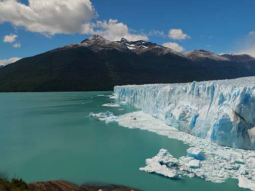 mountain ice berg near mountain under cloudy sky glacier