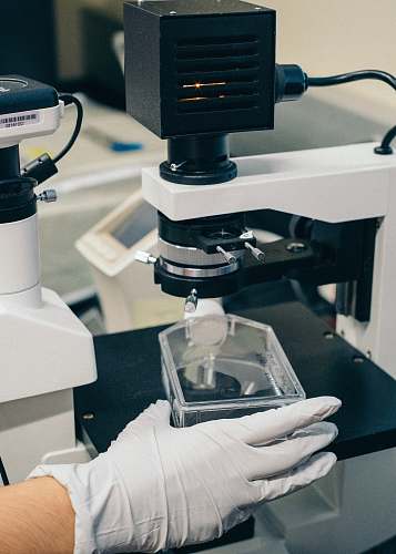 science person holding black and white microscope microscope