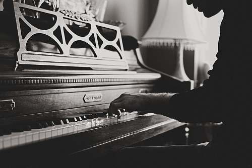 keys greyscale photo of man playing spinet piano close-up photo piano