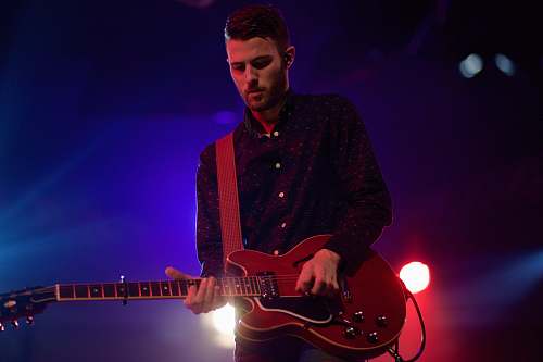 person man playing black electric guitar guitar