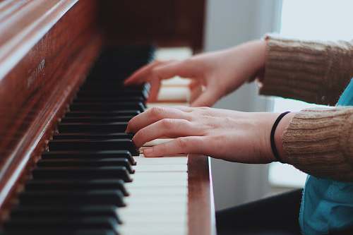 piano person wearing brown sweater playing piano pianist