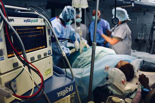 human group of people doing a surgery on a person inside the operating room clothing