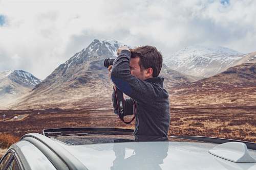 human man using camera inside car during day automobile
