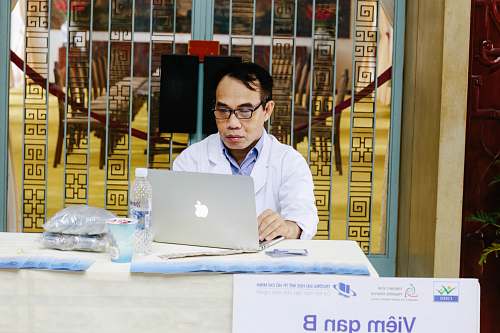 human man using silver MacBook near blue metal gate computer