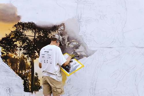 human man wearing black headphones near white wall paint people