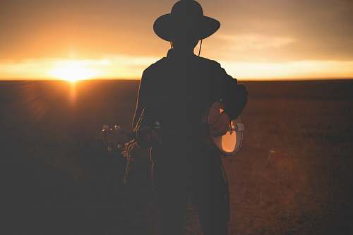hat man wearing hat playing guitar silhouette