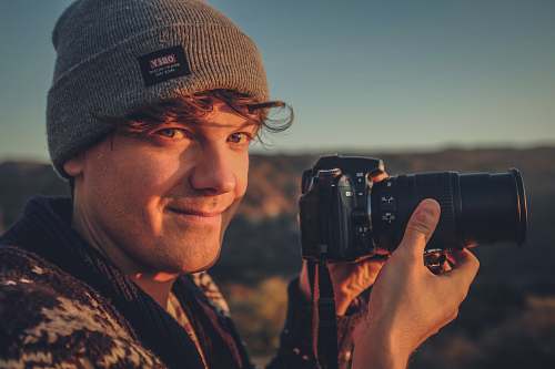 human person holding black camera electronics