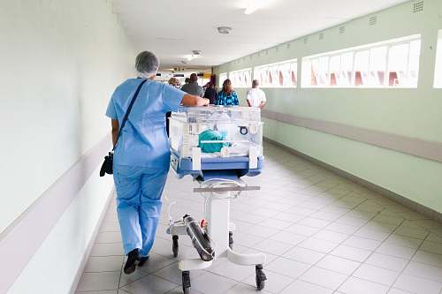 medical person walking on hallway in blue scrub suit near incubator hospital