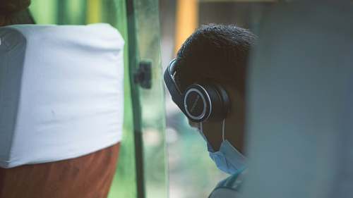human person wearing black wireless headphones and blue mask doctor