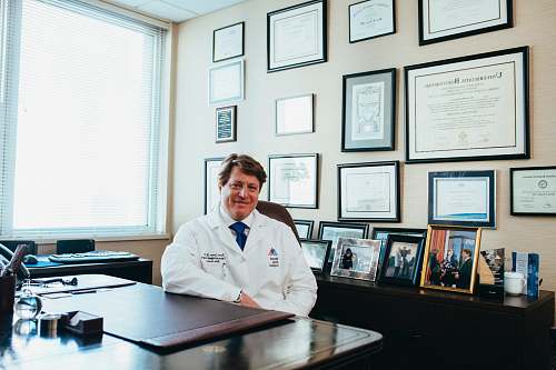 Apparel Smiling Man In White Shirt Sitting Behind Desk Clothing