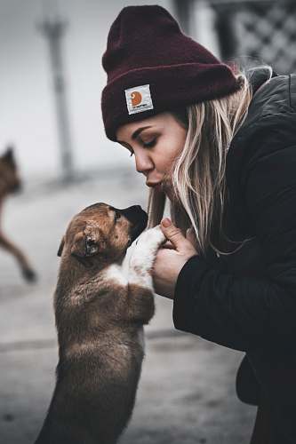 human woman about to kiss a tan puppy pet