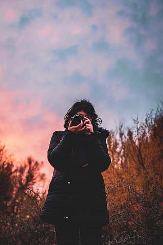 human woman in black jacket holding DSLR camera photo