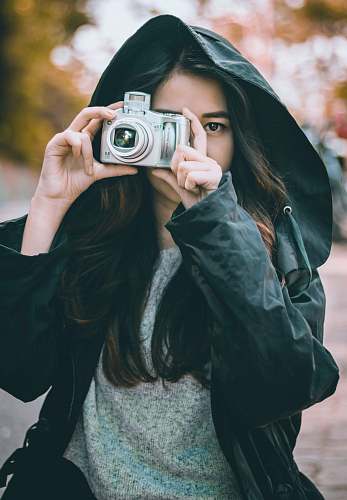 camera woman wearing jacket holding camera electronics