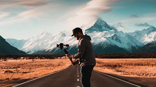 human man arranges his gimbal between empty narrow road person