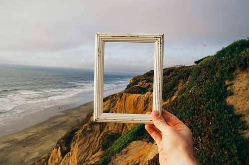 frame person hand holding photo frame ocean