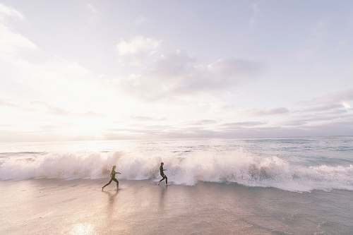 beach two person running on seaside beach during daytime ocean