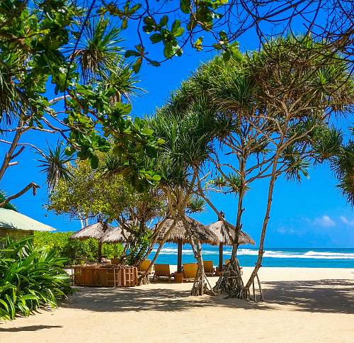 sea four huts at beach under blue skies during daytime indonesia