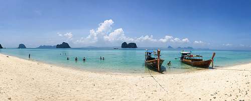 water people on beach beside two brown boats during daytime ocean