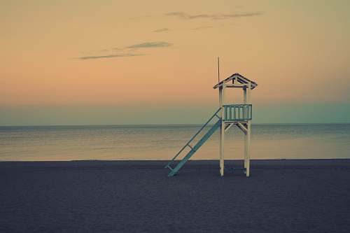 water white wooden lifeguard station near seashore at golden hour ocean